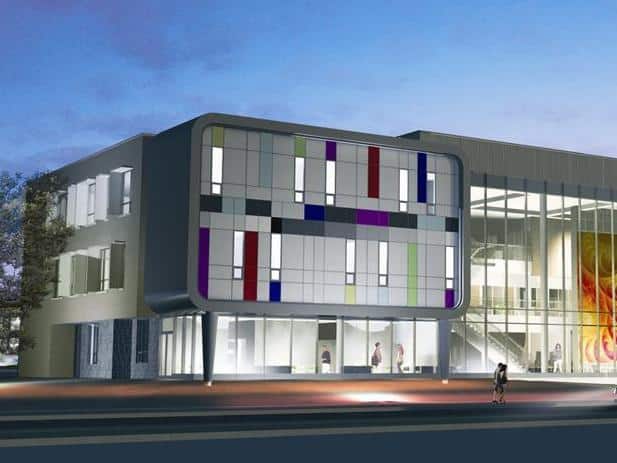 Modern building at twilight with a colorful façade of vertical and horizontal lines, large glass windows, and illuminated interior, reminiscent of the innovative architecture seen at the University of Waterloo, set against a backdrop of a clear evening sky.