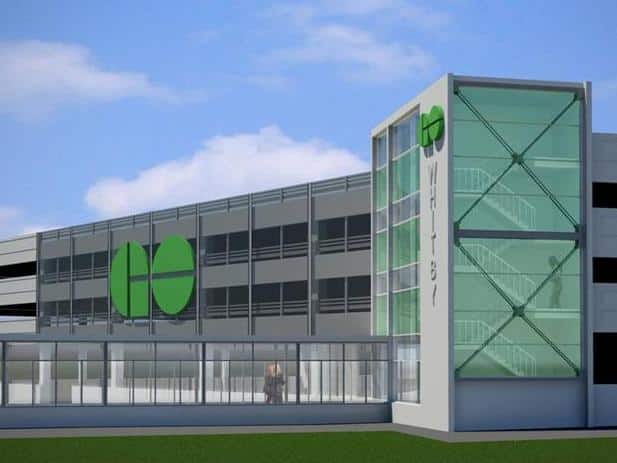 Modern two-story building with large windows, glass-enclosed stairwell, and a green circular logo featuring two vertical lines, reminiscent of the GO Transit branding.