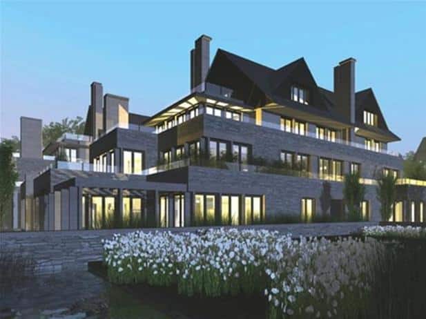 The Edgemere Residences is a large, modern multi-story building with numerous windows illuminated in the evening, surrounded by a garden of white flowers.