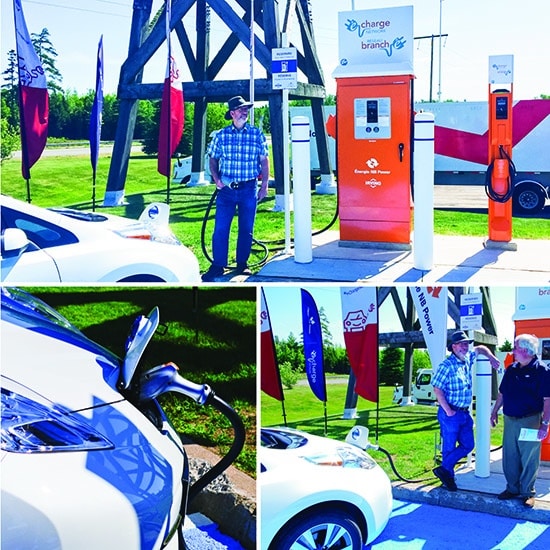 A man charges his electric vehicle at a multi-port station outdoors, surrounded by flags. Close-up of the charging plug captures the essence of battery-powered driving in New Brunswick.