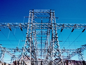 Steel lattice frames and electrical wires of a high-voltage power transmission system stand tall against a blue sky, bringing energy to homes far and wide.